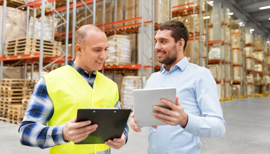 Real photo of a modern warehouse with workers using RFID scanners beside an optimization dashboard, efficient and bright.